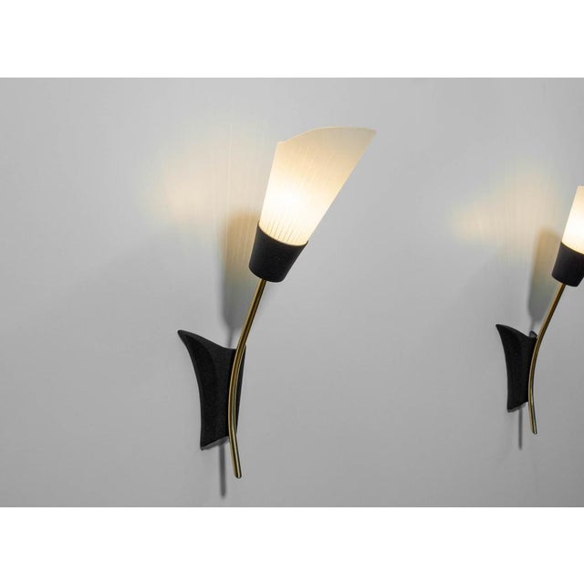 1960s vintage Swedish wall sconces crafted from brass, black-lacquered aluminum, and art glass shades. Featuring elegant,...