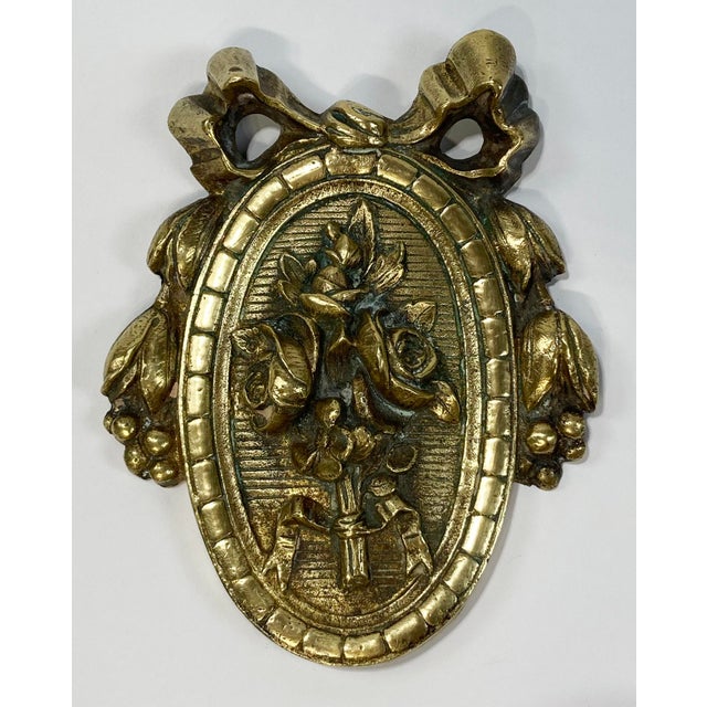 Vintage detailed brass door embellishment featuring ribbons to the top and flowers inside frame. A wonderful addition to...