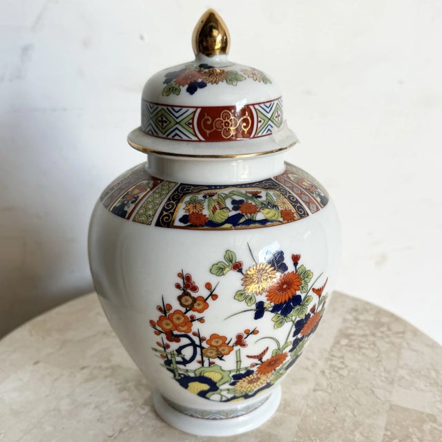 This beautiful vintage Asian porcelain ginger jar features intricate hand-painted floral motifs in vibrant hues of orange,...