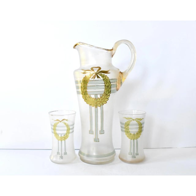 An antique blown, frosted glass lemonade or water pitcher and two glasses, hand-painted with a green neoclassical wreath...