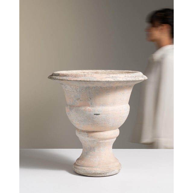 Painted pedestal urn planter in Weathered Antique White. The weathered antique white surface highlights flared urn form,...