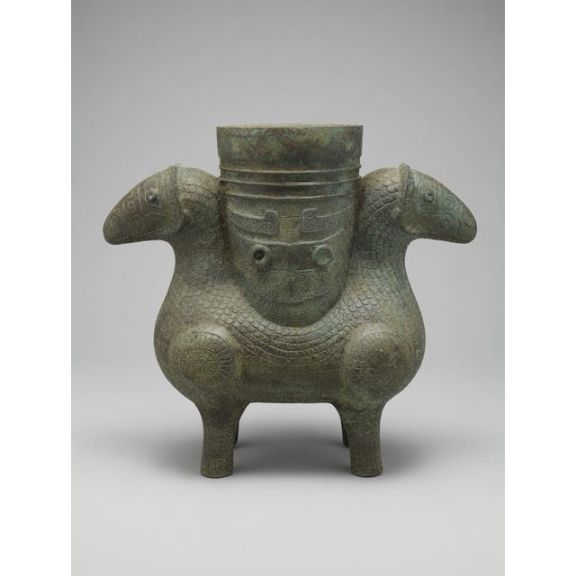 Offered here is a striking matched pair of archaistic Shang-style bronze ritual vessels, featuring opposed ram forms,...