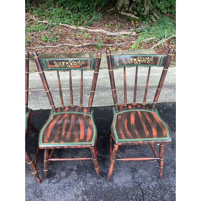 A charming set of four vintage dining chairs featuring a classic faux bamboo form with a beautifully aged, hand-painted...