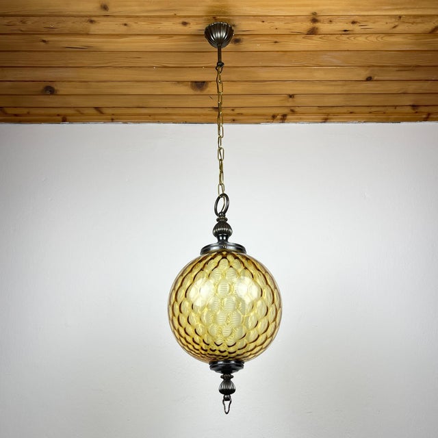Vintage yellow murano ball pendant lamp made in italy in the 1970s. the lamp consists of an amber ball with a white...