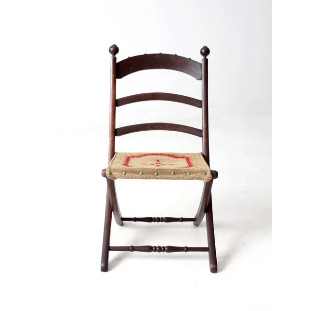 This late 19th century Victorian folding chair has a gracefully curved wood frame, three-slat back, turned stretchers, and...
