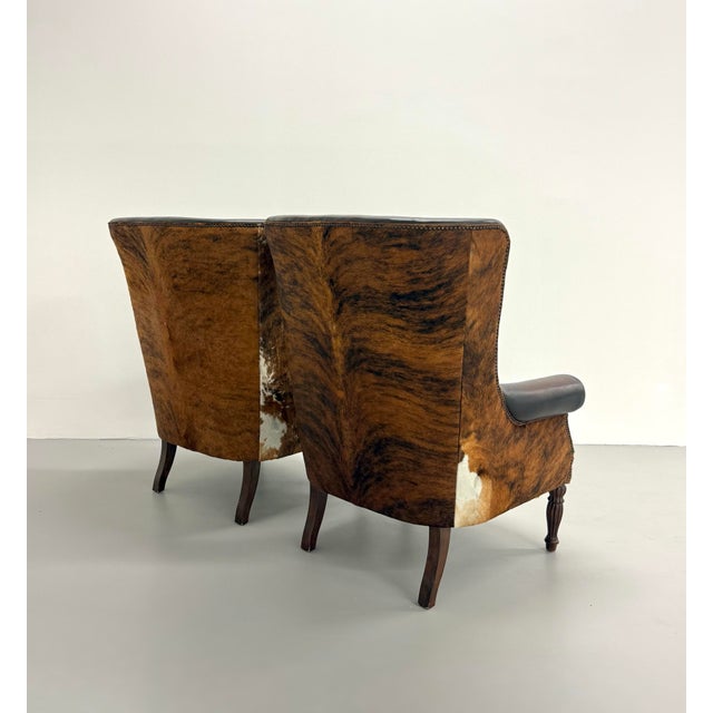 Striking pair of Bernhardt wingback lounge chairs upholstered in rich dark brown leather with contrasting hair-on-hide...