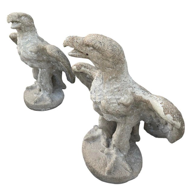 This is a powerful and evocative pair of vintage cast stone garden statues depicting eagles with their wings partially...