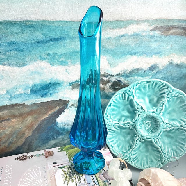 A Mid Century swung glass vase in a beautiful shade of blue with a 6 petal pedestal base.