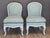 A pair of mid-20th century Louis XVI style slipper chairs with painted frames and carved detailing along the seat rails...