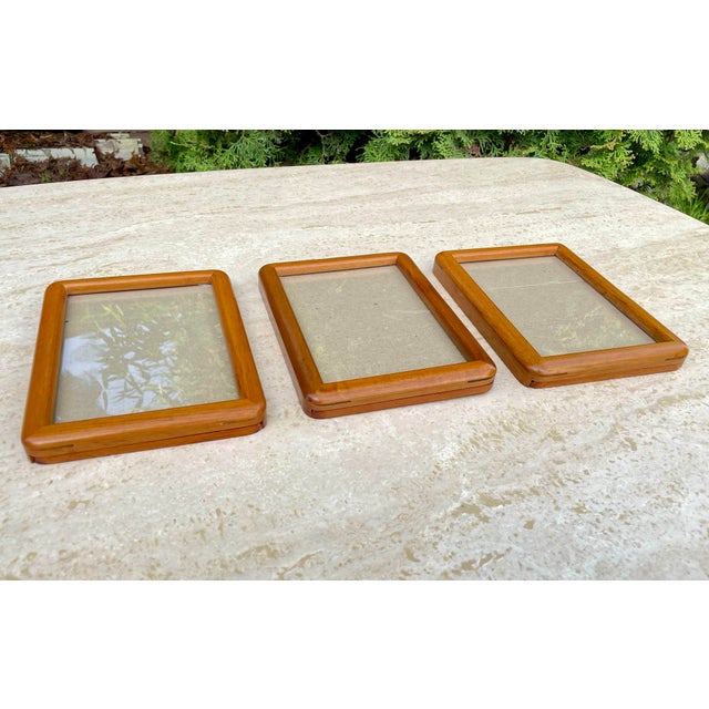 A set of three rounded Danish Modern style teak wood picture frames with wall hanging hardware.