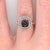 A rhodolite garnet glows in a raspberry red at the center of this solid 14K white gold ring, encircled by sixty-eight...