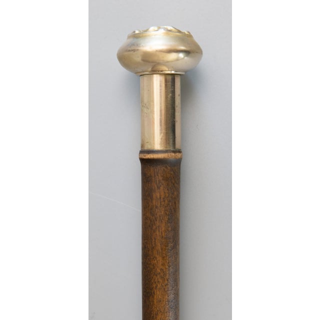 A superb antique English walking stick with a repoussé brass handle, walnut shaft, and brass ferrule, circa 1920. This...