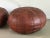 A pair of stitched leather poufs. The age and quality is evident by the gently worn brown patinated leather. Acquired from...