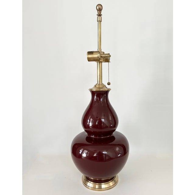 A single extra large double gourd ceramic lamp in a glossy oxblood or sang de boeuf red glaze by Ralph Lauren. Solid brass...