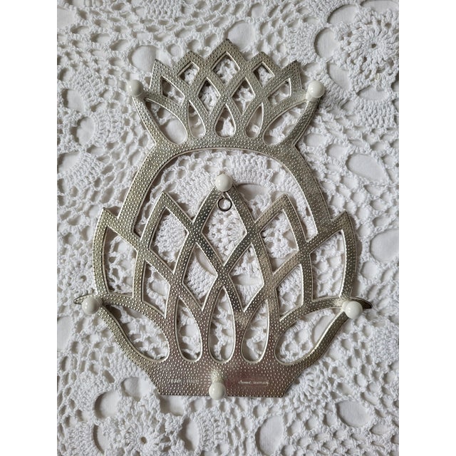 A metal pineapple trivet with hanger, marked 'Italy - Leonard Silverplate'. Measuring approximately 9” x 7 ½” x ½”....