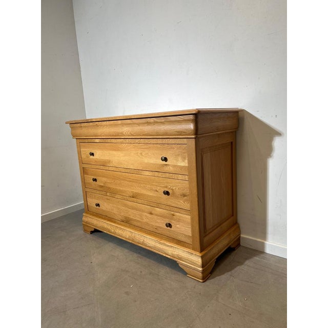 Elegant solid oak chest of drawers with a warm natural wood finish and classic rounded detailing. The piece features three...