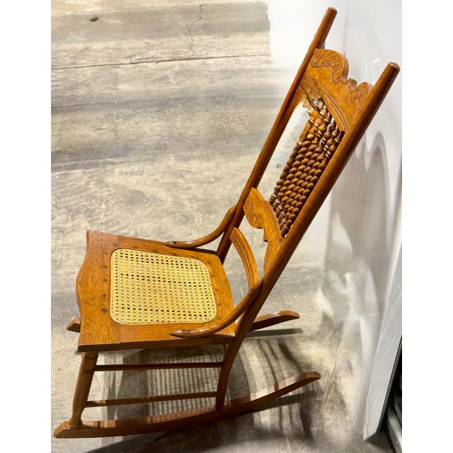This is an early 20th-Century small rocking chair featuring a classic oak frame with distinctive barley twist spindles...
