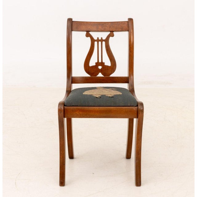 Children's Walnut Lyre Back Side Chair, with figural needlepoint upholstered seat. 22" H x 11.5" W x 11.5" H; seat: 12.25"...