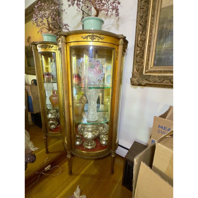 This beautiful piece features a half-round bow-front shape accent by curved glass panels and a mirrored interior backing....