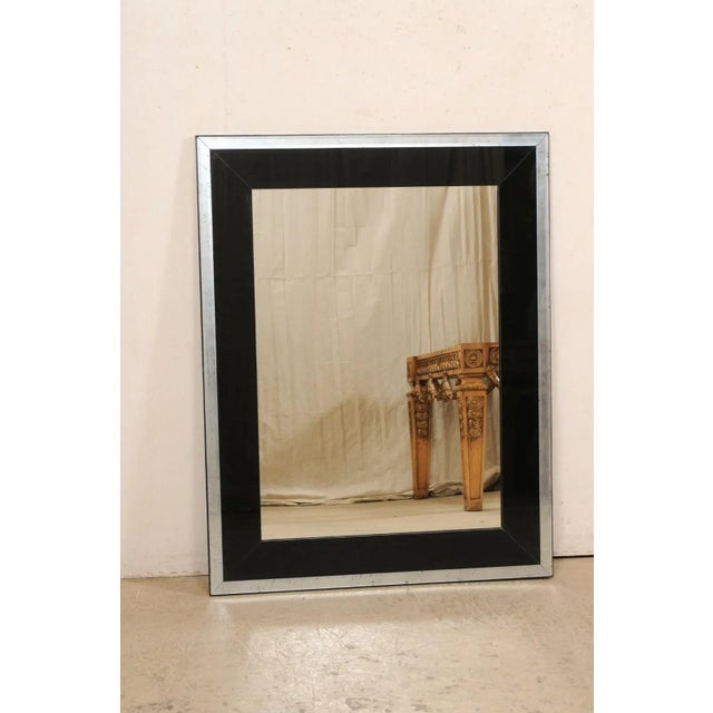 A sleek artisan-crafted rectangular wall mirror in a sophisticated black and antiqued glass surround. This nice-sized,...