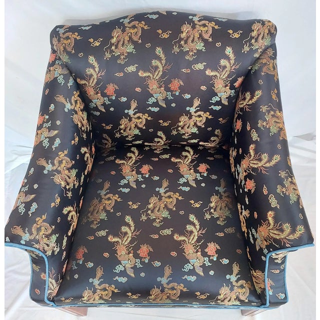 This imported Chinese satin brocade fabric features dragon and phoenix motifs across a dark sky. The primary colors are...