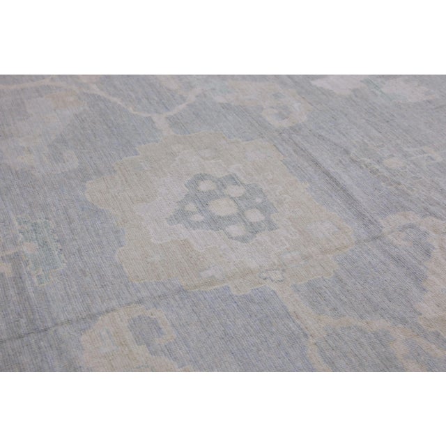 This modern Turkish Oushak rug is a stunning piece of art that has been handwoven using traditional techniques by skilled...