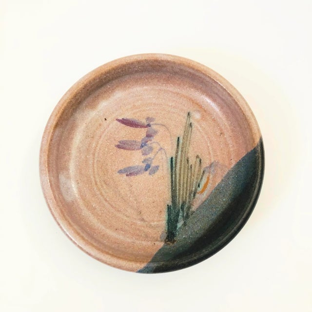 A vintage studio pottery circular tray. Purple and blue glazes with a lovely hand painted floral design in the center.
