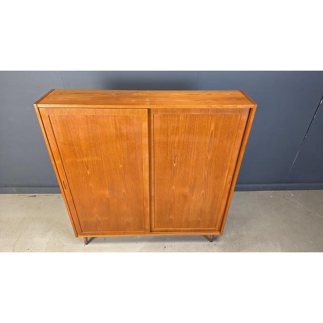 Solid teak cabinet designed by Poul Hundevad. Beautiful mid century piece with two sliding doors revealing lots of shelves...
