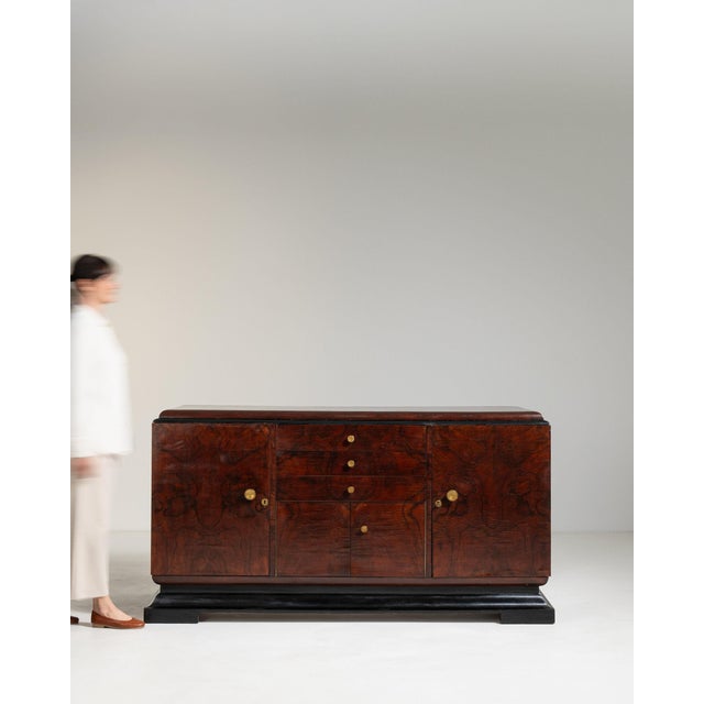 A sideboard whose dark mahogany, black lacquer trim, open door with drawers gives it real character at first glance. It...
