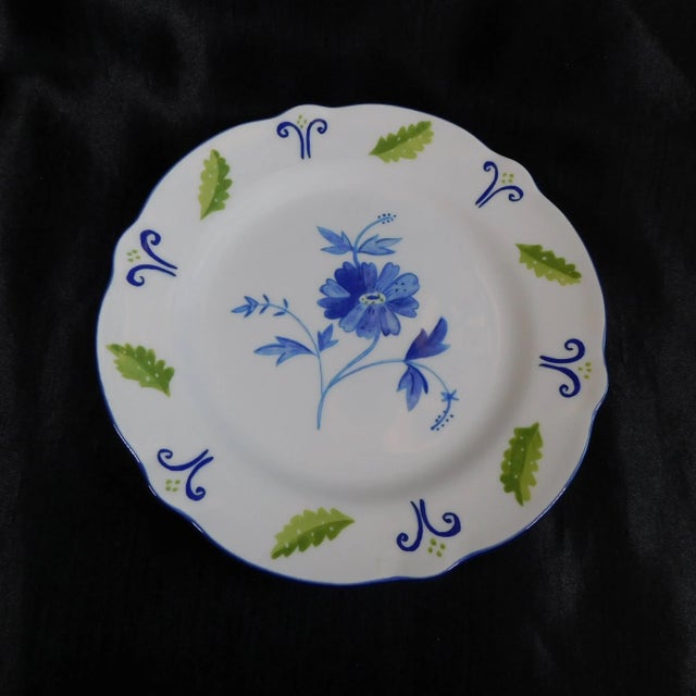 This is a Noritake Plate in Blue Spring by Susan Sargent. The plate is white with a blue flower center and blue and green...