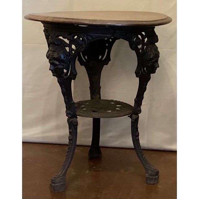 The base features three legs decorated with detailed figural masks. Made of heavy cast iron three splayed legs, joined by...