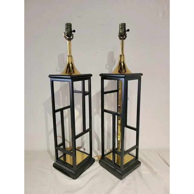 Beautiful tall lantern lamps are designed in the style of Tommi Parzinger feature brass tone metal and black frame. Our...