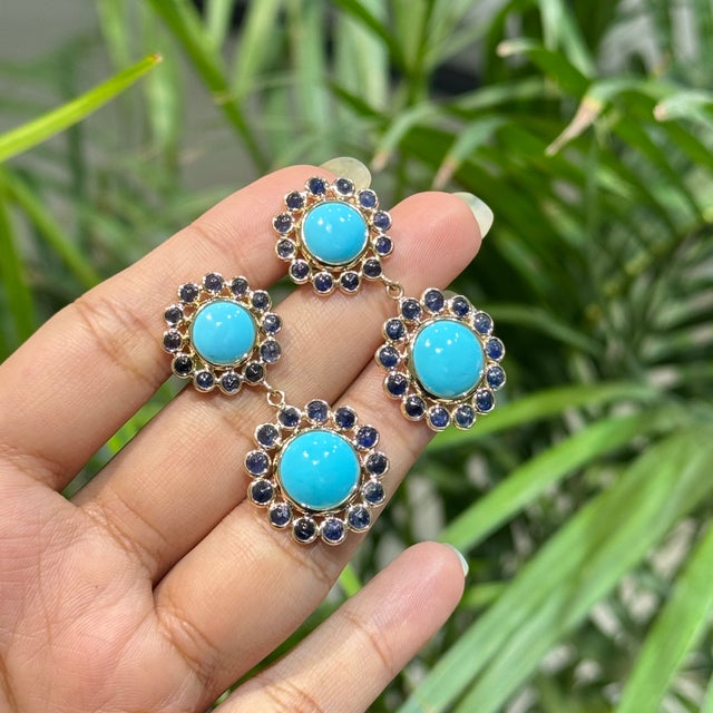These two-tier drop earrings feature 20.43 carats of turquoise cabochons and blue sapphires, set in 14k yellow gold. The...