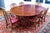 A stately, well-crafted and beautifully polished mahogany extension dining table with a reddish-brown finish, wide...