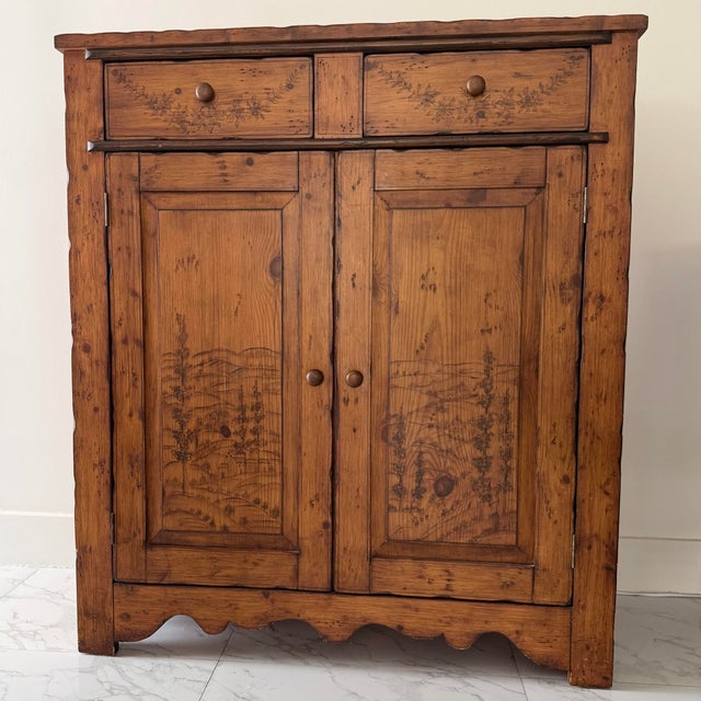 Distinctive Sarreid jelly cupboard crafted in wood with intricate pyrography-style landscape, architectural, and botanical...