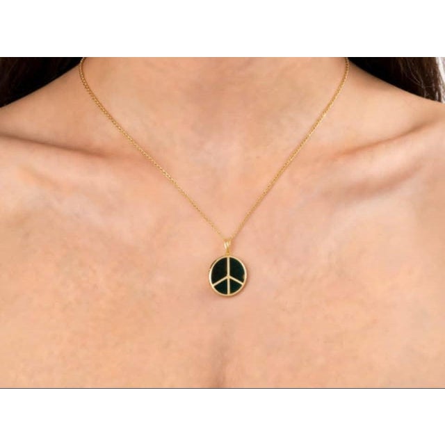 Modern 14K yellow gold pendant slide featuring a bold peace sign design with a black onyx center. Estate piece with sleek...