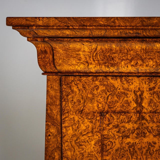 Biedermeier secretary with pyramidal case. The piece rests on plinth legs and features three drawers of varying heights in...