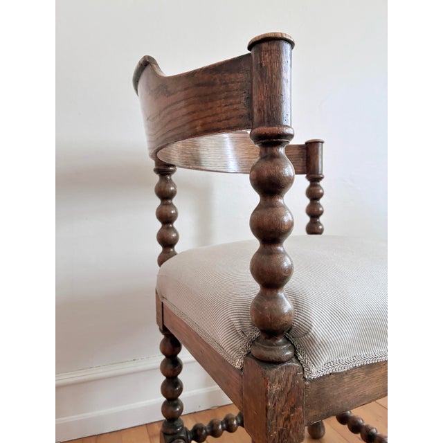 An antique corner chair in solid wood, likely beech, with a dark stained finish. This English chair features turned bobbin...
