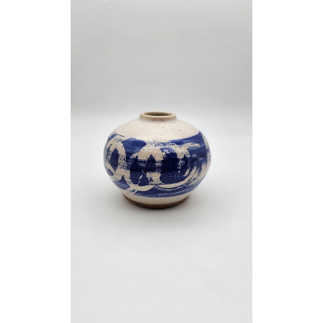 Hand-thrown stoneware bud vase featuring expressive cobalt blue brushwork over a warm speckled glaze. The rounded form and...