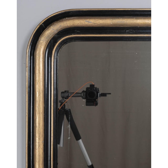 A 19th century French Louis Philippe mirror with curved top corners, black painted and gilt finish with subtle incised...