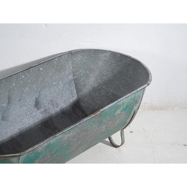 Industrial galvanized-metal storage container, most likely a farm trough or service reservoir, originally from central...