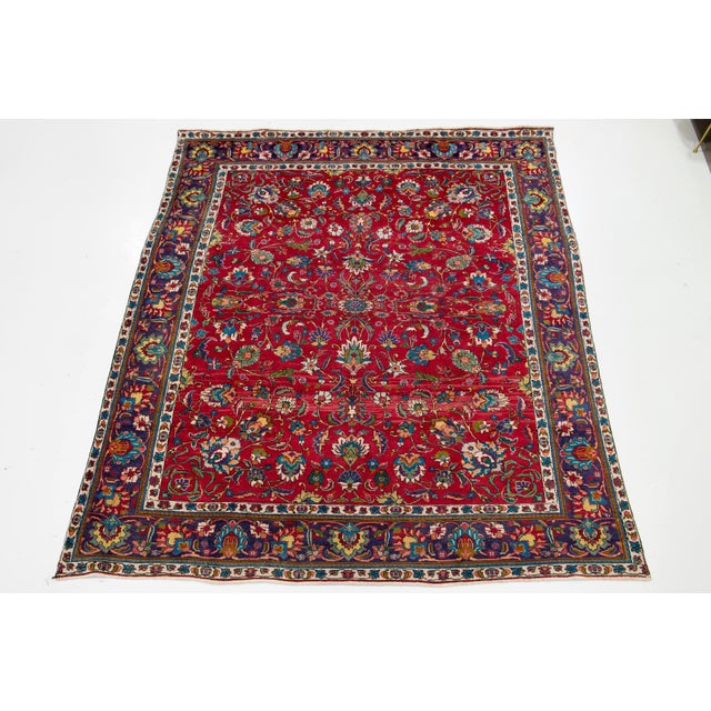 This vintage red hand-knotted wool Tabriz rug features a stunning floral design with multicolored accents. This rug...