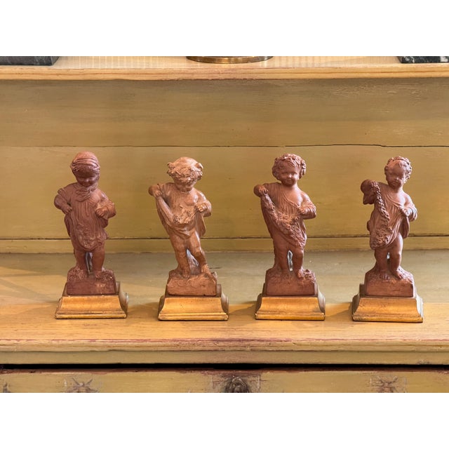 Set of four Borghese terracotta figures representing the Four Seasons, each modeled as a putto with seasonal motifs. Rich...