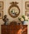 A Federal-style giltwood convex mirror crowned with a carved eagle, its wings outstretched above a laurel motif—an...