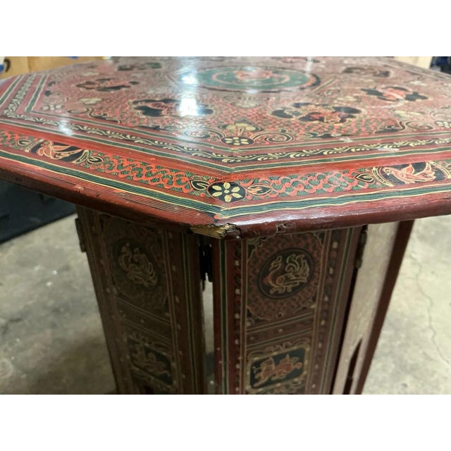 A small octagonal side table with arched apron panels and a top fully hand painted with flowers, scrolls and a central...