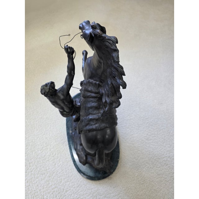 A bronze sculpture depicting one of the "Horses of Marly," fashioned after the famous 18th-century marble originals by...