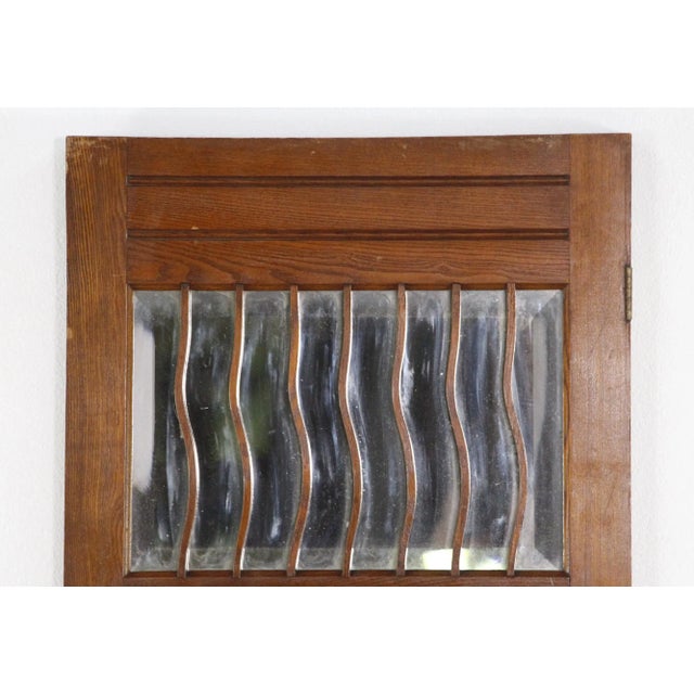 Narrow two panel oak door with foliate carvings and a beveled mirror lite at the top with curved wood going across it....