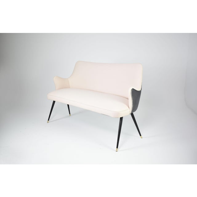 An Italian sofa by Osvaldo Borsani, dating to the early 1950s, distinguished by its winged back, slender tapered legs, and...
