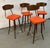 This is a vintage mid-century modern swivel bar stool featuring a bright orange vinyl seat and a curved wooden laminate...