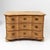 A three-drawer commode made of light softwood with a distinct serpentine front. The piece features a triple-curved shape...